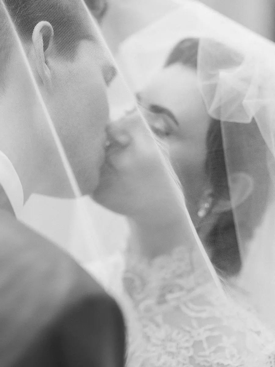 Bride and groom kissing under veil – artistic and delicate wedding photography