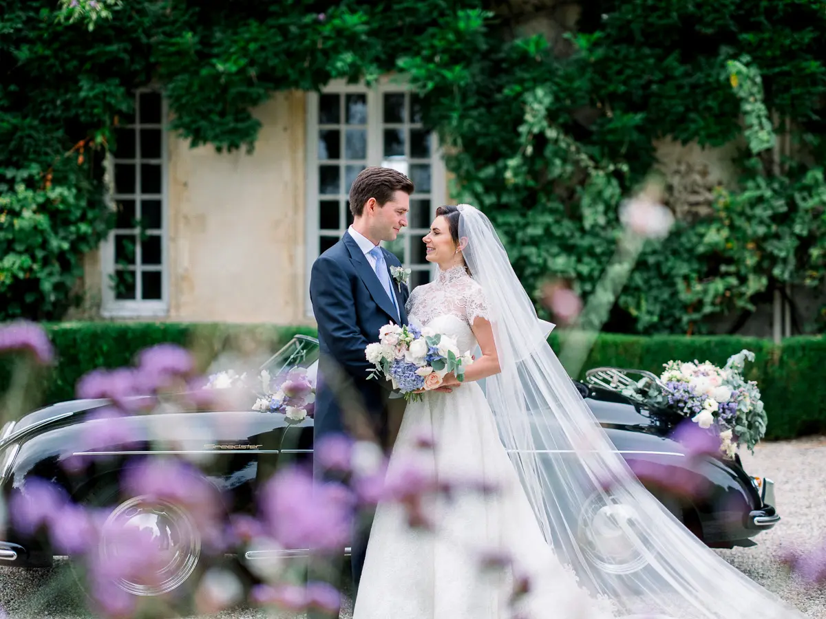 Couple de mariés élégants devant une voiture ancienne dans un château français – photographie mariage éditorial intemporelle