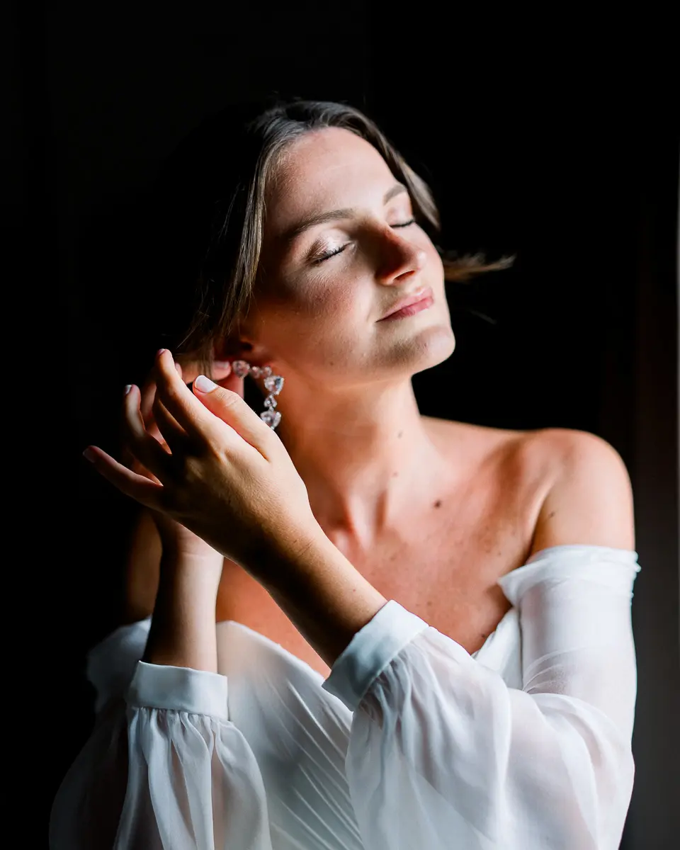 portrait de mariée mettant ses boucles d’oreilles pendant les préparatifs de mariage