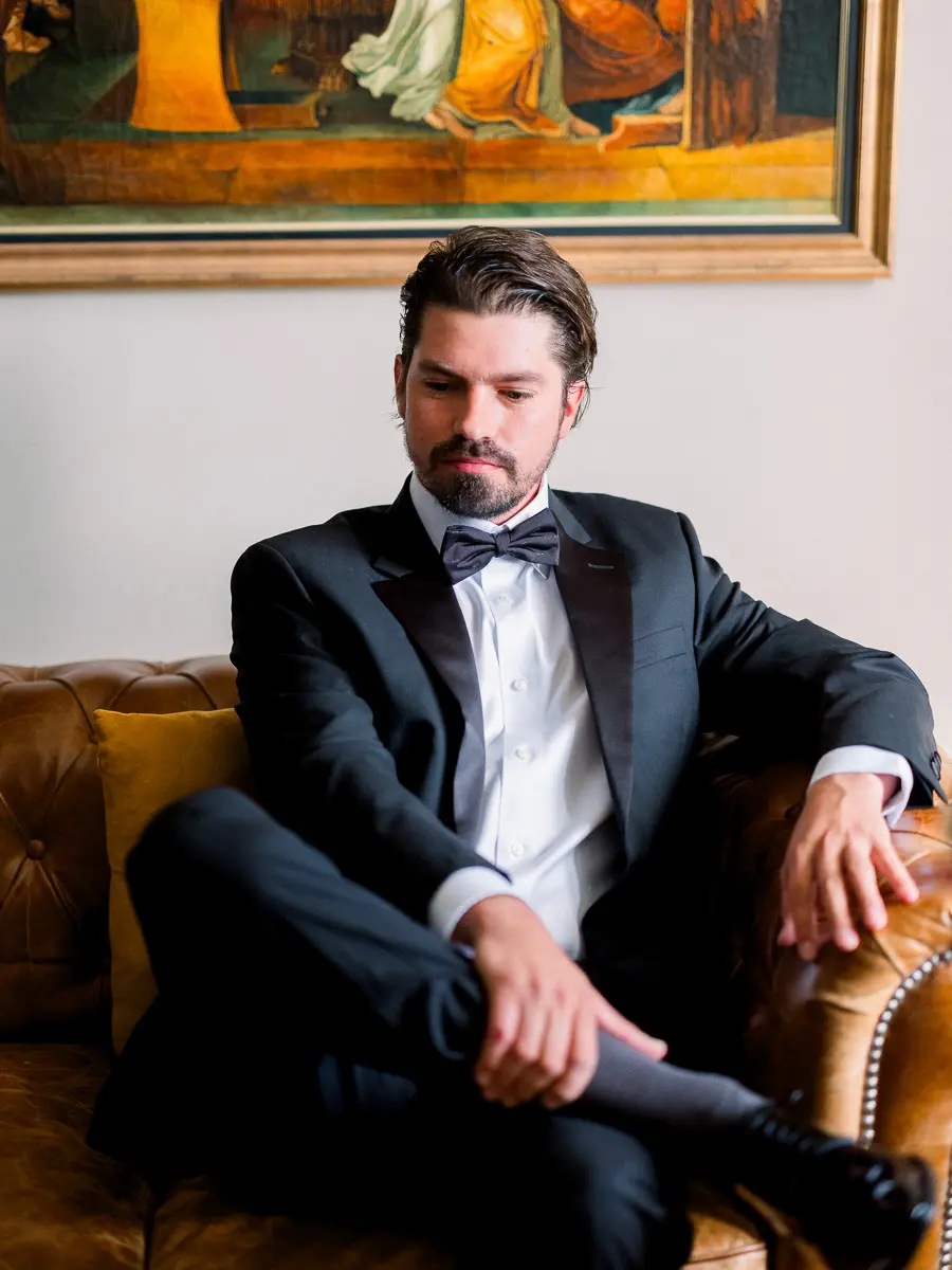 Marié en costume assis sur un canapé – portrait élégant et lumière naturelle